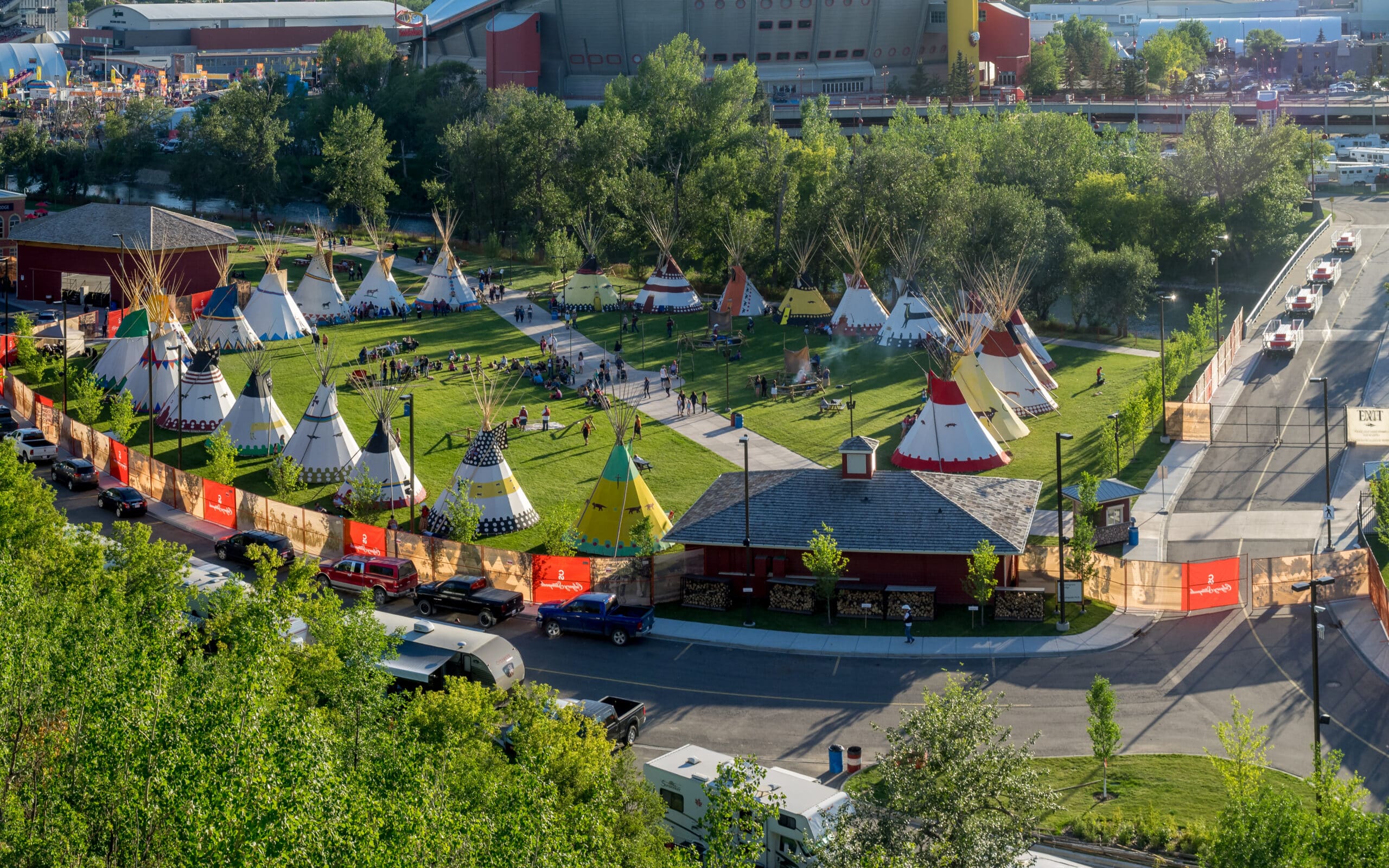 Birds eye view of tipis in a park with a gathering of people.